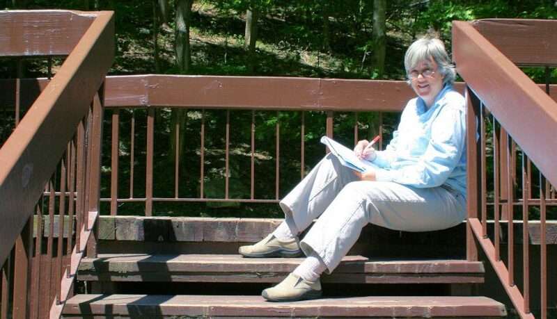 Terry Modica writing on the steps outdoors at Pipestem Lodge