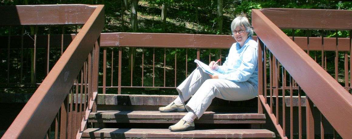 Terry Modica writing on the steps outdoors at Pipestem Lodge